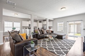 A spacious living room with a sectional sofa, a glass coffee table, and a patterned rug.