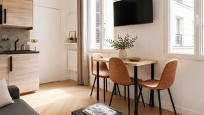 A modern kitchen with a black countertop, a built-in oven, and a window with curtains. - TheBlueStay 350 - Stunning Apt in République (Paris)
