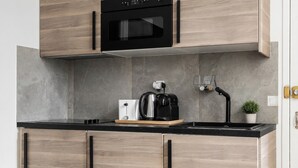 A modern kitchen with a microwave, coffee maker, and kettle on the countertop. - TheBlueStay 350 - Stunning Apt in République (Paris)
