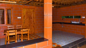 A kitchen with a wooden table and chairs, a sink, and a tiled floor. - Heaven In Woods (Mekkarai)