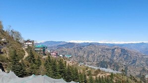 Un paisaje montañoso con vistas a un valle, algunos edificios y cielo despejado.