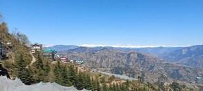 A mountainous landscape with a view of a valley, a few buildings, and a clear sky. - The fagu Retreat (Theog)