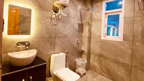 Un baño con suelo de mármol, lavabo, inodoro, ducha y ventana.