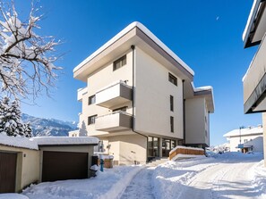 A modern multi-story building with a snow-covered exterior, a visible garage, and a clear sky. - Modern holiday apartments in Jenbach (Jenbach)