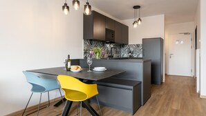 Eine moderne Küche mit einer zentralen Kochinsel, Pendelleuchten und einer Essecke mit zwei Stühlen.