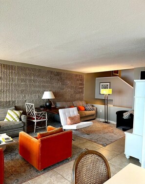 A modern living room with a sofa, armchair, and a dining area. - 21 Ocean Drive unit 902- Water Views in the North Shores Community. (Rehoboth Beach)
