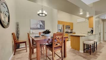A modern kitchen with wooden cabinets, a central island, and a dining area with a wooden table and chairs.