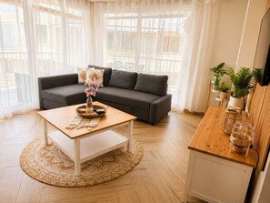 A living room with a sofa, coffee table, and a small kitchen area with a counter and plants. - Peaceful 3-bedroom apartment in Salou near the beach (Salou)