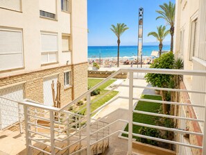 A balcony with a view of a beach, palm trees, and a tall structure. - Peaceful 3-bedroom apartment in Salou near the beach (Salou)