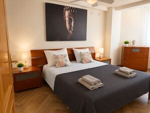A bedroom with a bed, nightstands, a dresser, a ceiling fan, a Buddha statue, and a wall-mounted painting. - Peaceful 3-bedroom apartment in Salou near the beach (Salou)