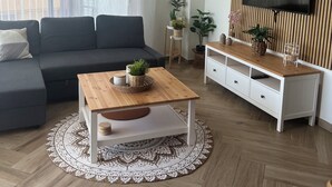 Ein modernes Wohnzimmer mit einer Couch, einem Couchtisch, einem Fernseher und einem Deckenventilator.