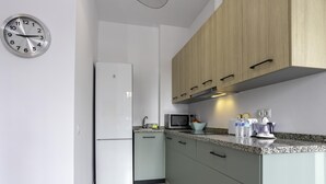 A modern kitchen with a refrigerator, microwave, sink, and granite countertop. - Sunstay Luzon Loft I Málaga (Málaga)