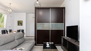 A modern living room with a sofa, a coffee table, a TV, and a sliding glass door. - Sunstay Luzon Loft III Málaga (Málaga)