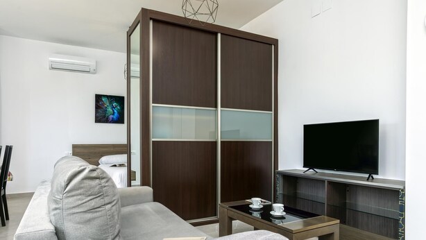 A modern living room with a sofa, a television, a coffee table, and a wardrobe. - Sunstay Luzon Loft III Málaga (Málaga)