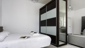 A modern bedroom with a bed, a wardrobe, a grey sofa, and a TV. - Sunstay Luzon Loft III Málaga (Málaga)