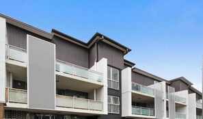 A modern multi-story residential building with balconies, large windows, and a flat roof design. - Warm & Convenient Home Near the Lake in Pemulwuy (Pemulwuy)