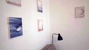 Ein Zimmer mit einem Bett, einer Wandlampe und vier gerahmten Kunstwerken.
