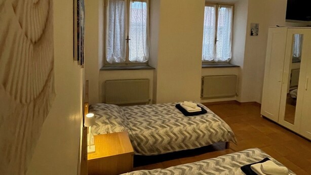 Ein Zimmer mit zwei Betten, einem Schreibtisch, einem Stuhl, einem Fernseher und einem Kleiderschrank.