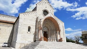 Ein historisches Gebäude mit einem großen Bogenportal, Stufen, die davor führen, und einer Kuppel auf dem Dach.