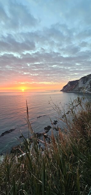 A coastal sunset view with cliffs and vegetation. - Apartment center Ancona, a stone's throw from the port and the Cathedral. (Ancona)