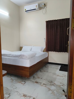 Un dormitorio con cama, aire acondicionado, cortina y suelo de mármol.
