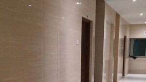 A corridor with marble walls and floors, doors, and recessed lighting.