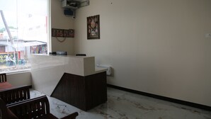 A hotel reception area with a marble floor, a reception desk, and a window overlooking a street.