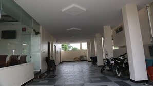 A hallway with a tiled floor, a seating area with chairs, a motorcycle, and a television mounted on the wall.