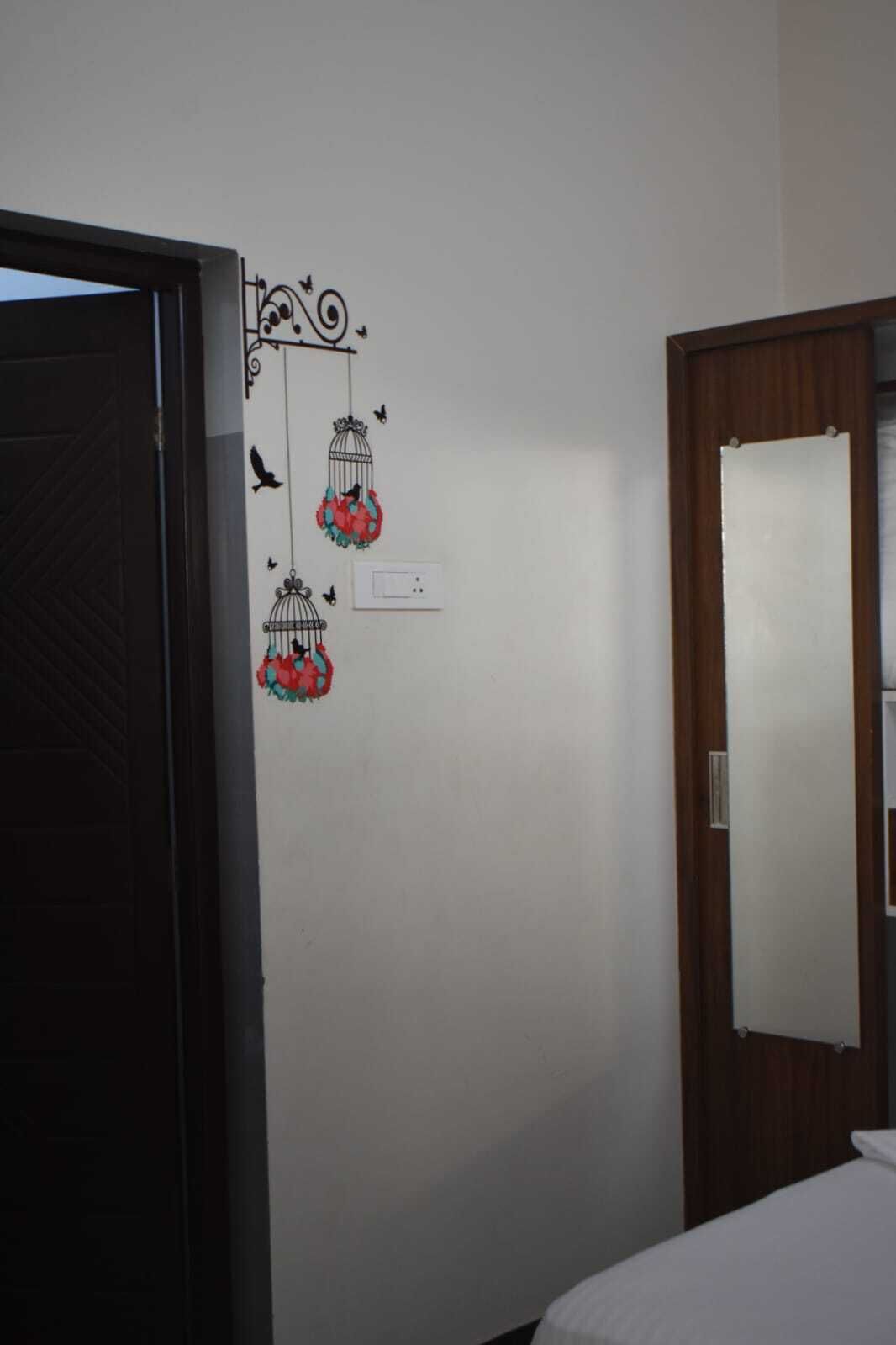 Una habitación con puerta de madera, pared blanca y decoración de jaula de pájaros, además de una cama.