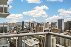A cityscape with high-rise buildings, a clear sky, and a distant mountain range. - High-Rise Retreat | Panoramic Ocean & City Views (Honolulu)