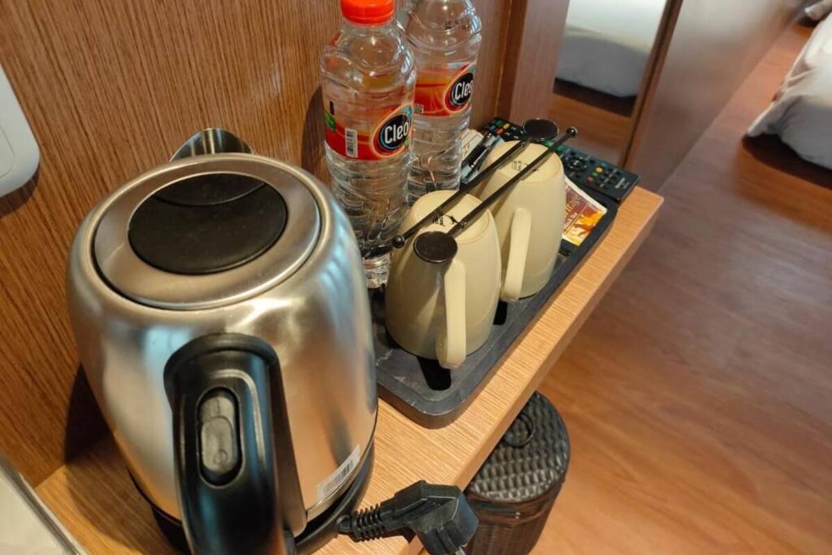 Una encimera de cocina con una tetera, dos botellas de agua, un tostador y un control remoto.