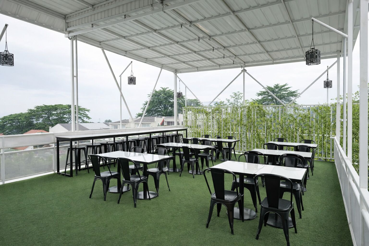 An outdoor patio with tables and chairs, a white roof, and green artificial turf.