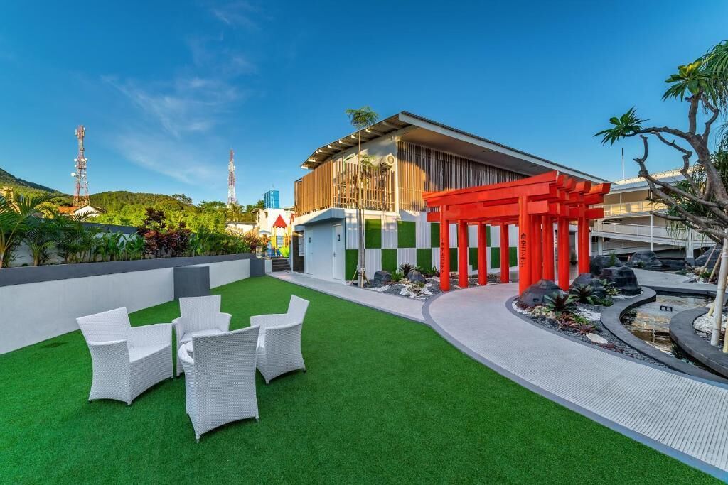 A modern building with a red torii gate, artificial grass, and white wicker furniture.