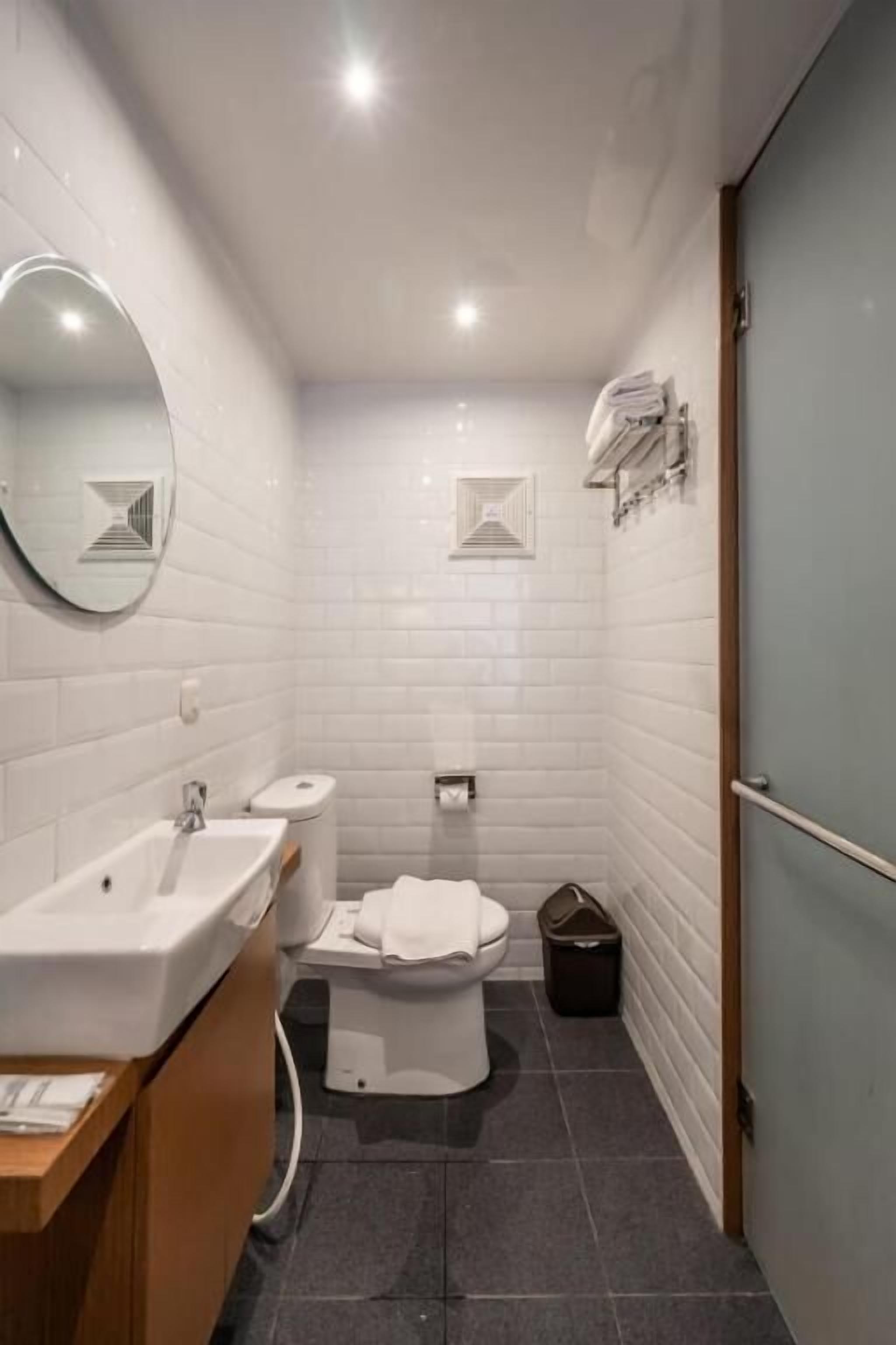 A modern bathroom with a sink, toilet, and mirror.