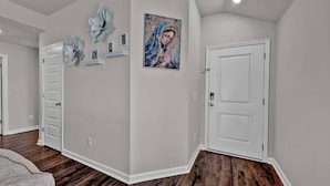 A hallway with a white door, a framed artwork, and a light switch on the wall.