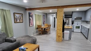Un saló amb un sofà, una taula de centre de fusta i una zona de menjador amb cadires i taula.