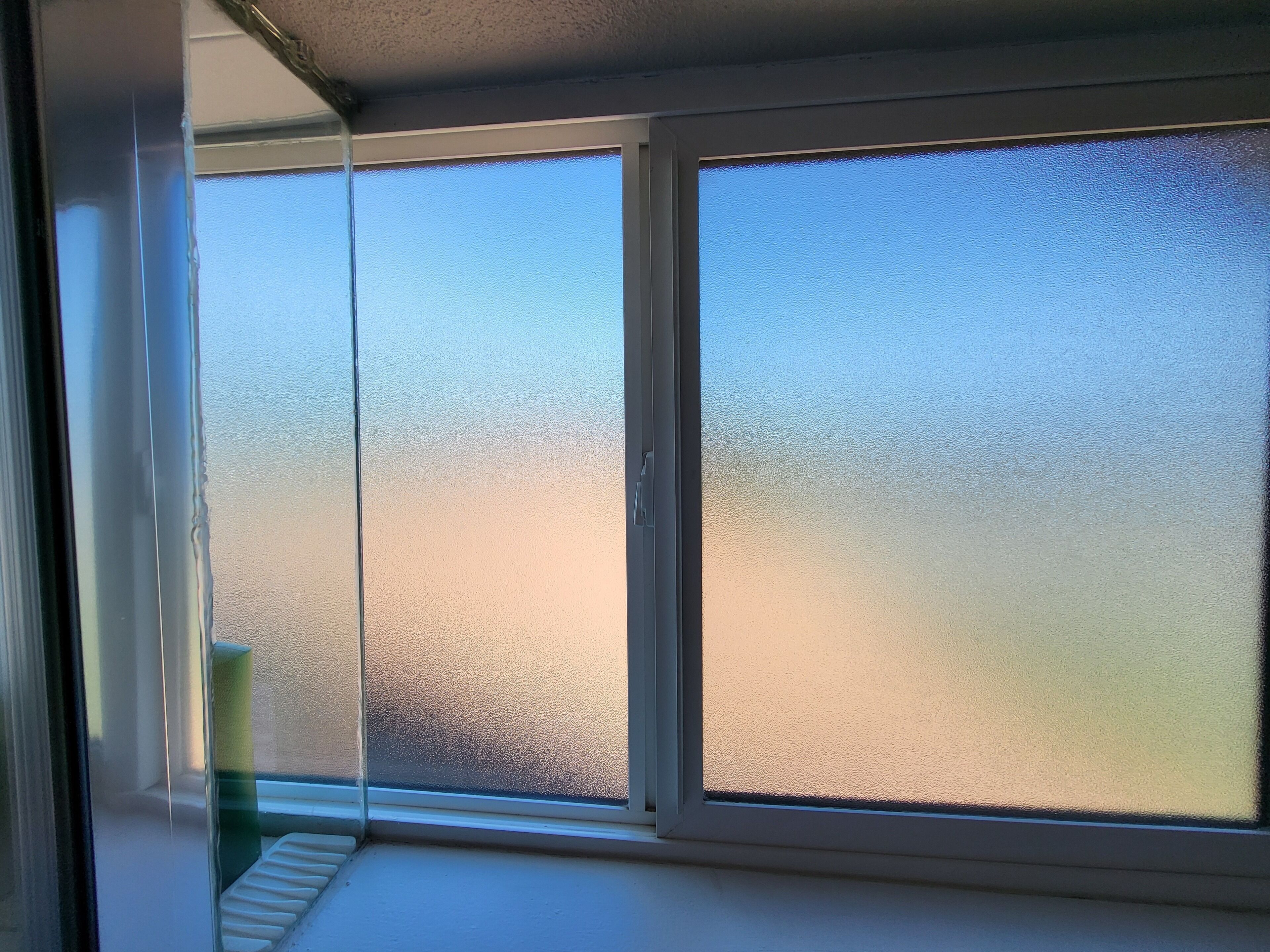 A room with frosted glass windows, a white ceiling, and a visible corner of a white wall.