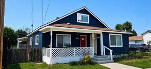 A two-story residential house with a front porch, a red door, and a mailbox. - Grove Street Couplet #1  (Baker City)