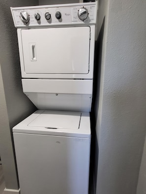 A stacked washer and dryer unit with control knobs and a door.