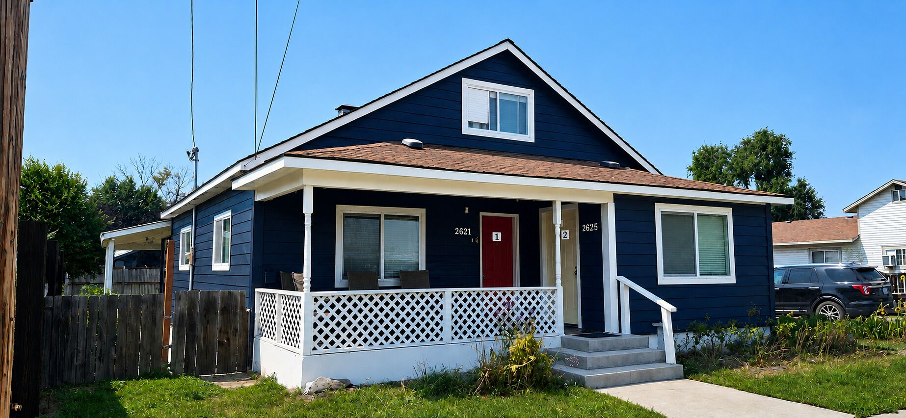 A two-story residential house with a front porch, a red door, and a mailbox.