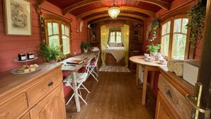 Une pièce chaleureuse aux murs en bois, avec une longue table et un lit à baldaquin.