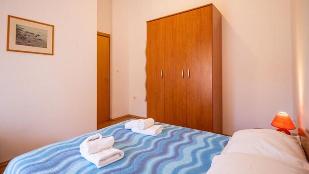A bedroom with a bed, a wardrobe, a framed picture on the wall, and a bedside lamp. - Apartment in Pasman Near Adriatic Beaches (Pasman)