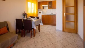 A compact living space with a dining area, kitchenette, and a door leading to another room. - Apartment in Pasman Near Adriatic Beaches (Pasman)