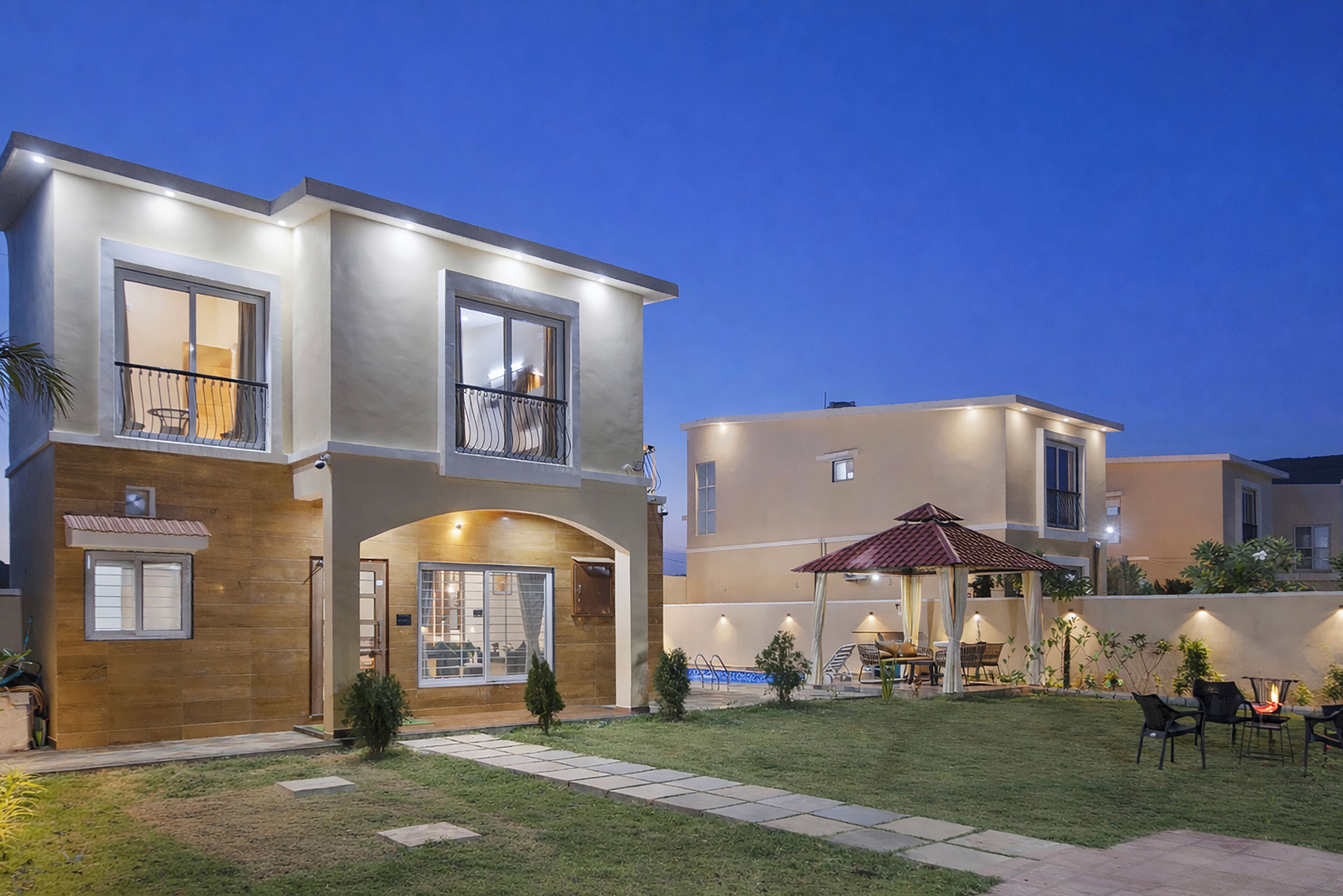 A two-story house with a patio, a covered seating area, and a small pool.
