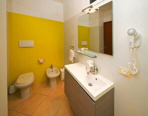 A bathroom with a yellow wall, a white sink, a bidet, a toilet, a mirror, and a hairdryer on the wall. - Ferienwohnung fur 4 Personen in Imperia (Imperia)