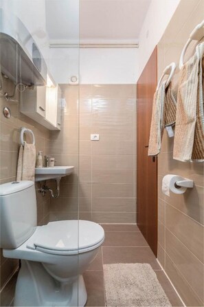 A bathroom with a toilet, sink, and shower area. - Studio in Valbandon Near Brijuni National Park (Fazana)