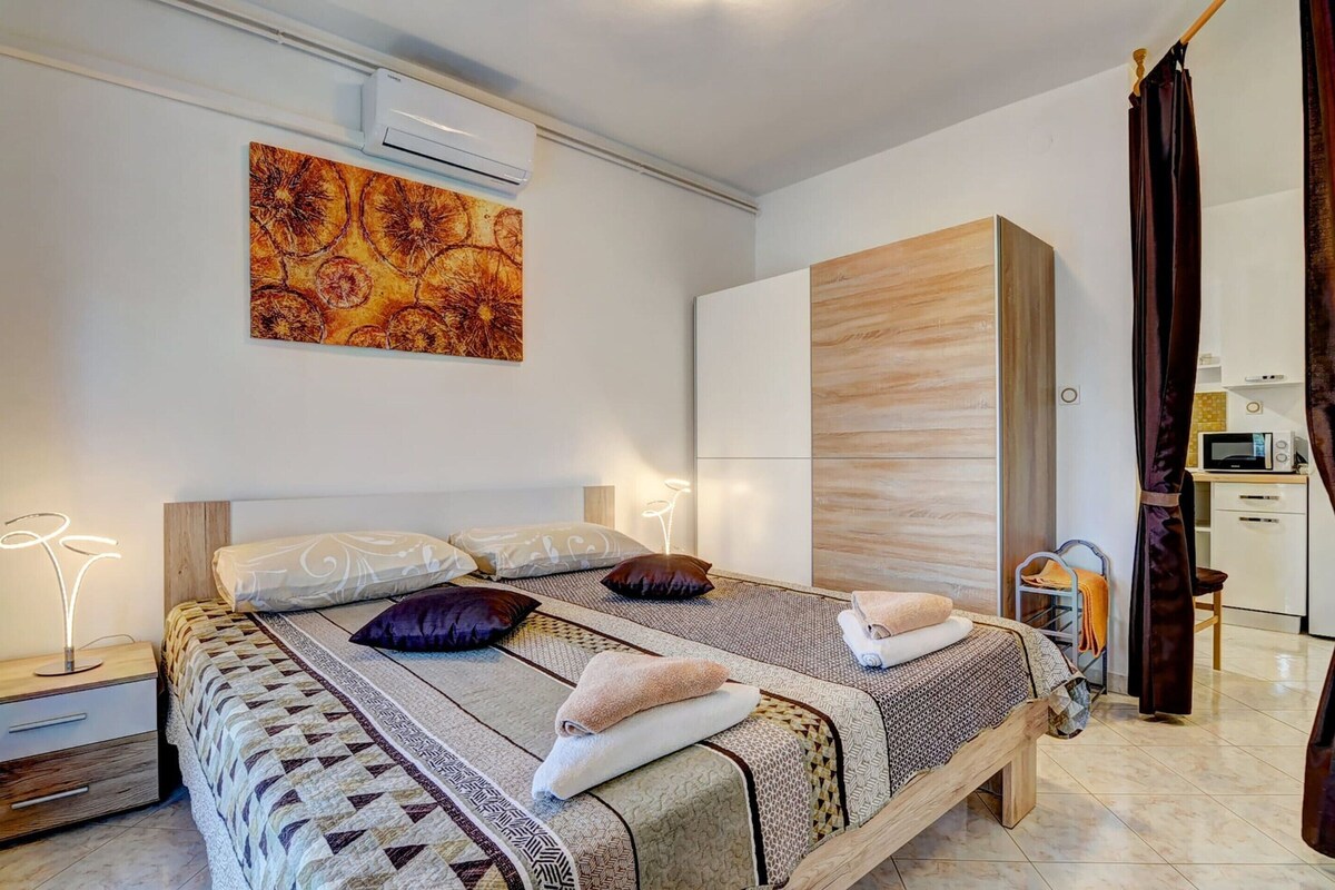 A modern bedroom with a bed, bedside tables, a wardrobe, and an air conditioning unit.