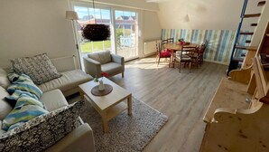 Amplia sala de estar con sofá, mesa de centro y mesa de comedor.
