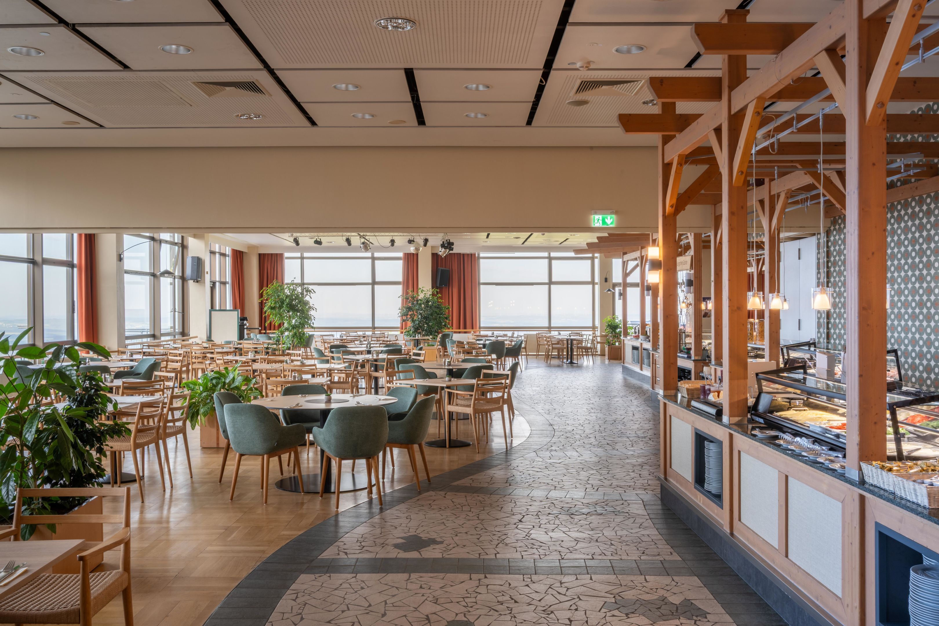 A spacious dining area with multiple tables and chairs, large windows, and a buffet counter.