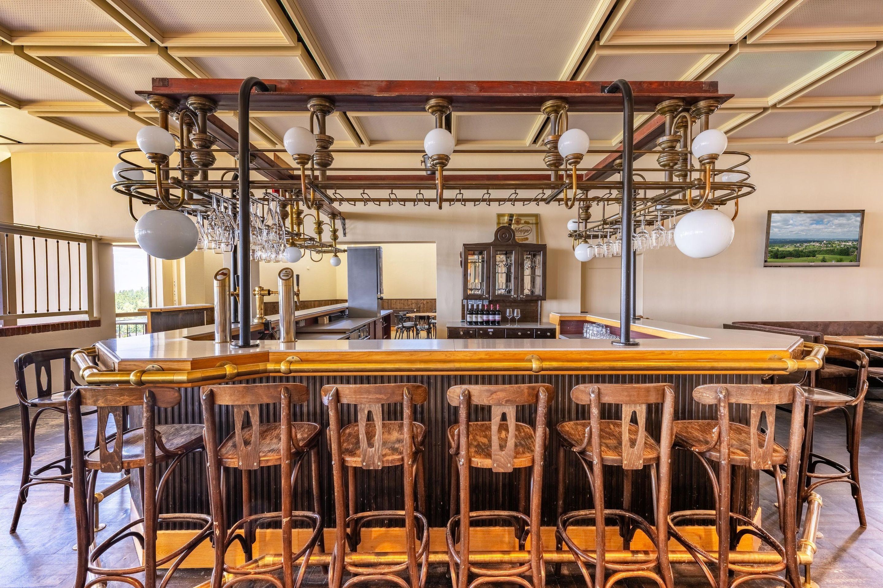 A bar area with wooden chairs, a bar counter, and a chandelier.